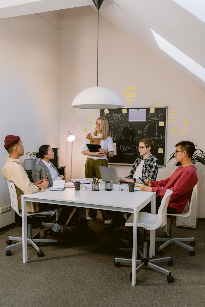 A diverse team of young professionals brainstorms in a modern office setting with a casual yet focused atmosphere.